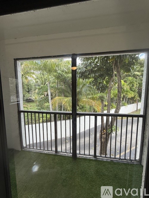 A balcony with a metal railing overlooking a road with trees.