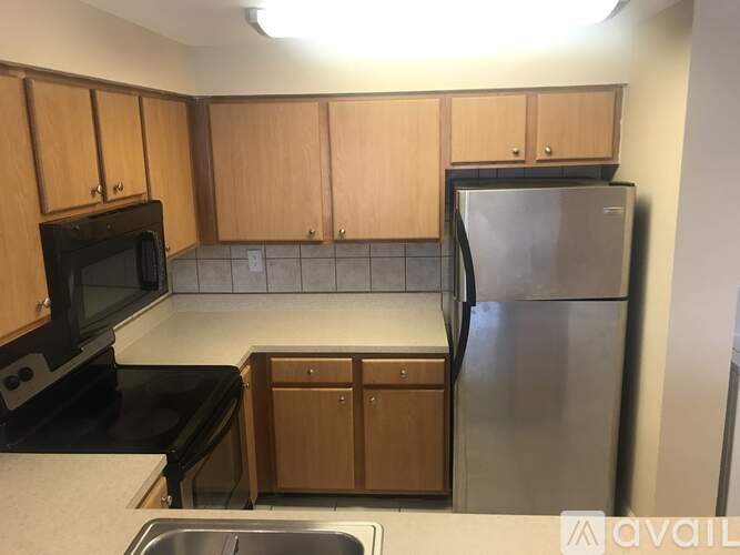 A kitchen with wooden cabinets and a stainless steel refrigerator.