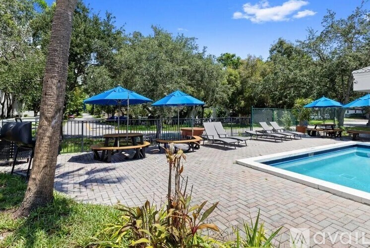 A pool area with blue umbrellas and a brick patio.