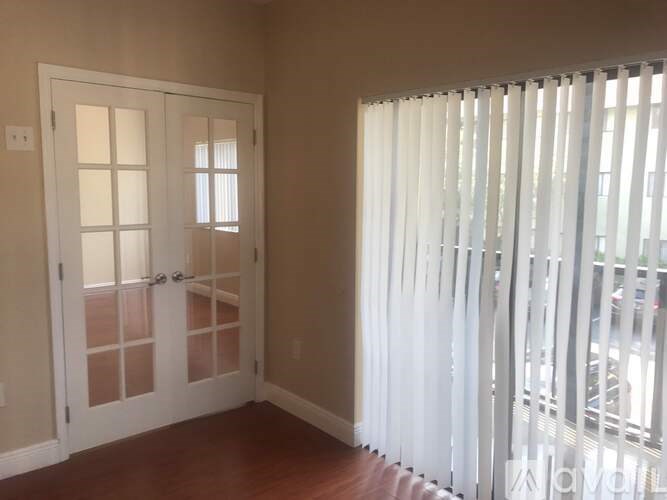 A room with a white door and a window with white blinds.