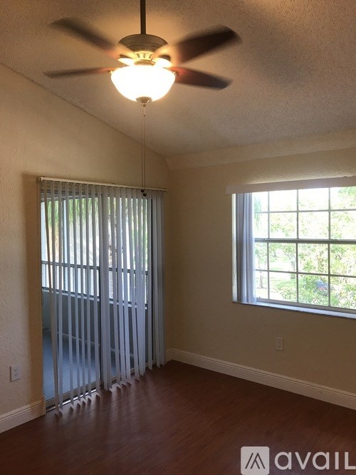 A room with a ceiling fan and a window with blinds.