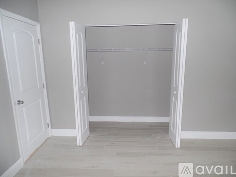 A white closet with a grey wall and wooden floor.