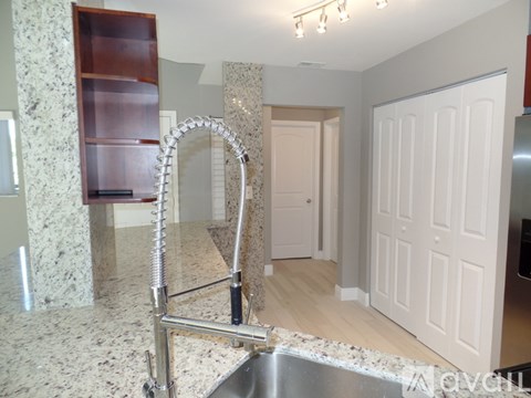 A kitchen with a granite countertop and a stainless steel sink.
