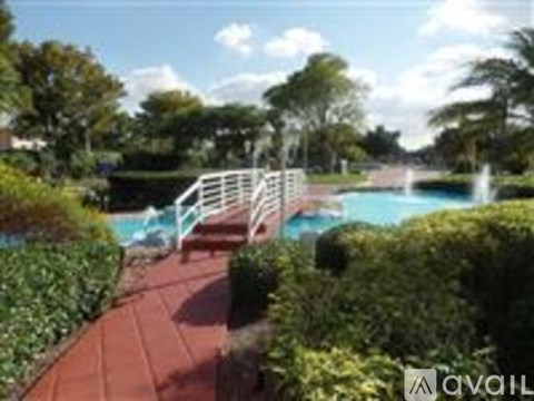 A pool surrounded by greenery and a white fence.