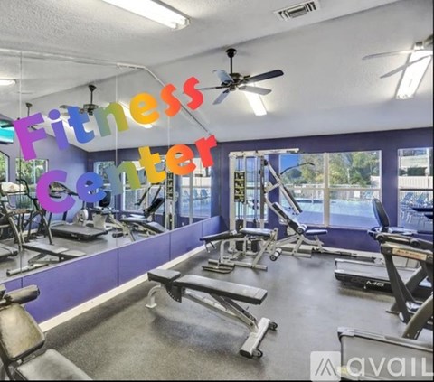 A fitness center with a variety of equipment and a large mirror on the wall.