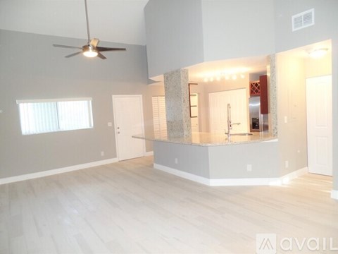 A spacious room with a ceiling fan and a bar area.