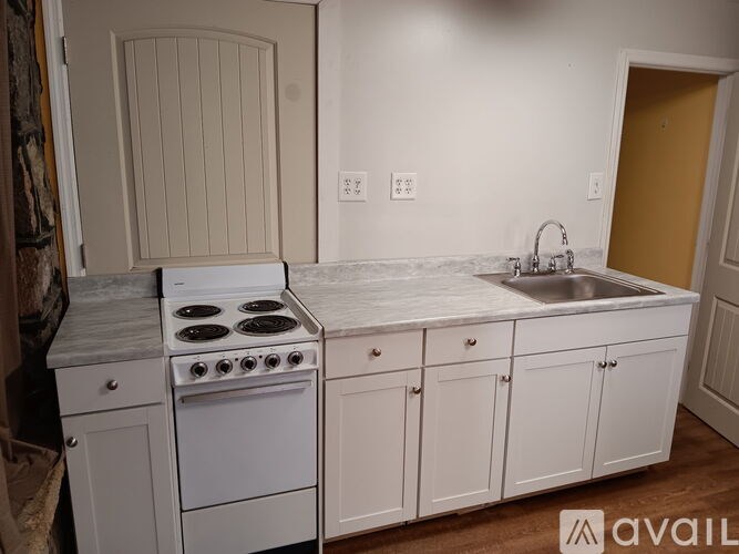 A kitchen with a white stove and cabinets.