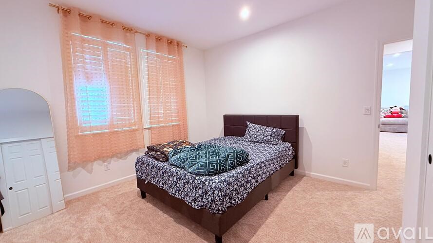 A bedroom with a bed and a window with orange curtains.