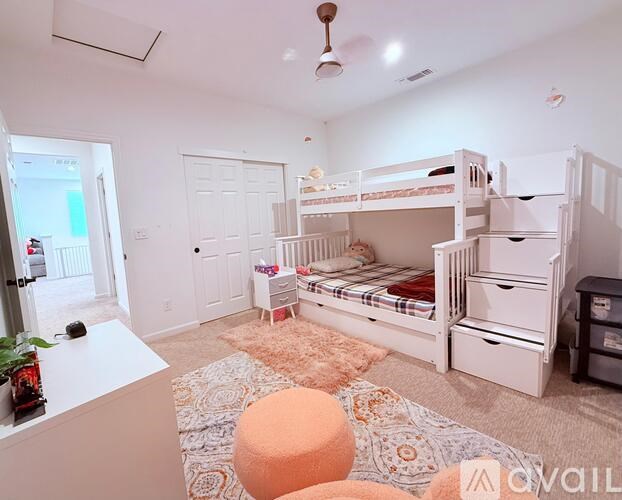 A room with white walls and a ceiling fan, furnished with a bunk bed and a desk.