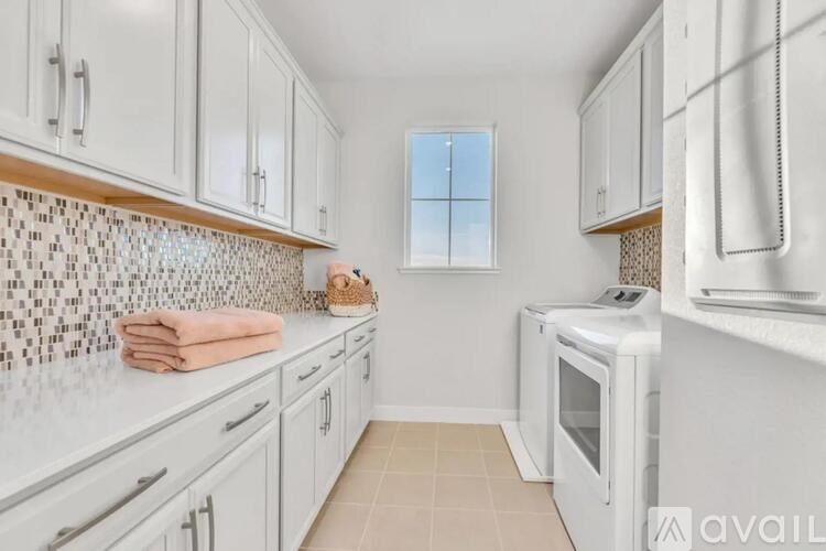 A kitchen with white cabinets and a tiled backsplash.