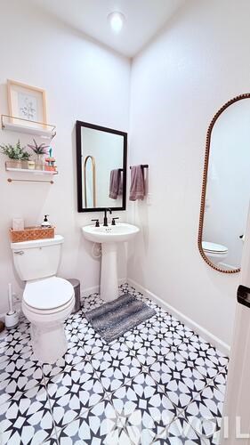 A white toilet sits next to a sink in a bathroom with a black and white floor.