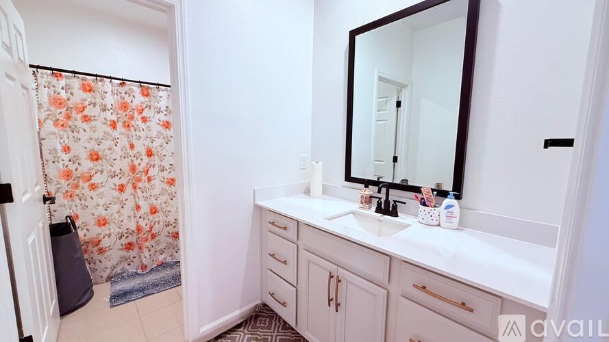 A bathroom with a floral shower curtain and a white vanity.