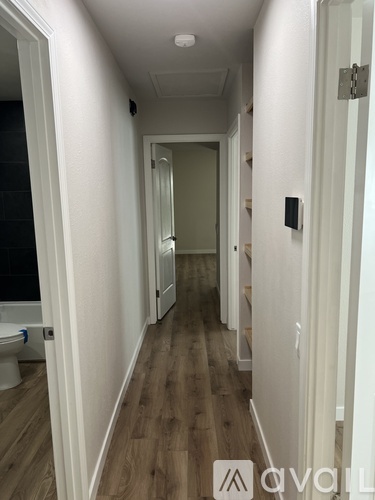 A long hallway with wood floors and white walls.