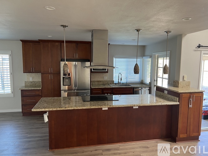 A kitchen with a granite countertop and wooden cabinets.
