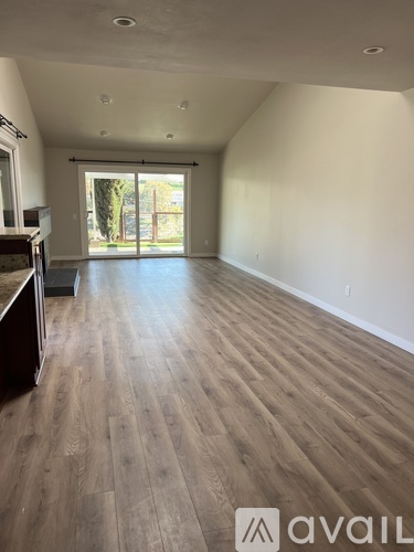 A room with wooden flooring and a large window.