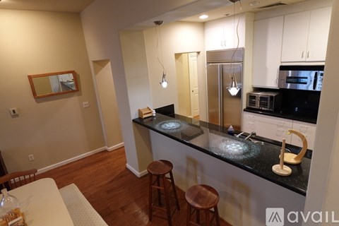 A kitchen with a black counter top and wooden stools.