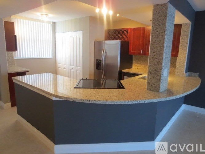 A kitchen with a curved counter and a refrigerator.