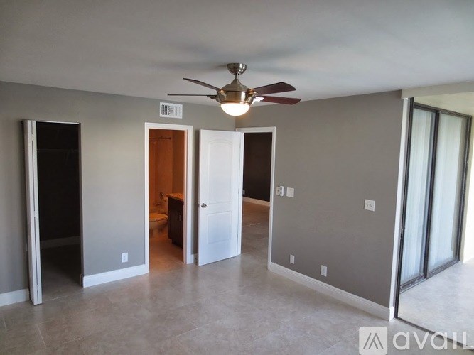 A room with a ceiling fan and a doorway leading to another room.