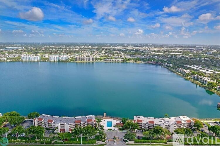 A bird's eye view of a waterfront property with a swimming pool and apartment buildings.