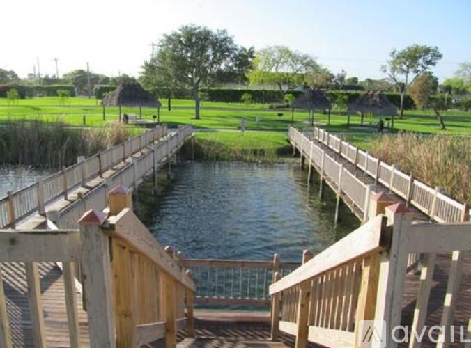 A wooden bridge over a body of water with a green field in the background.