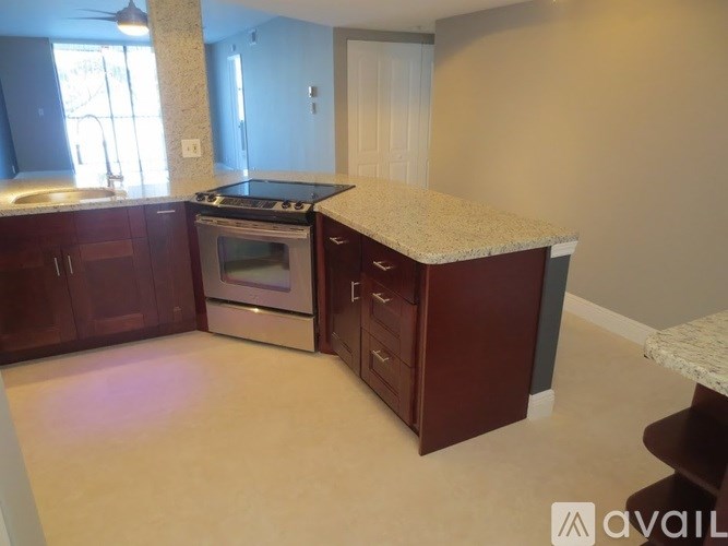 A kitchen with a granite countertop and dark wood cabinets.