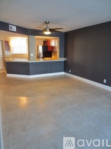 A spacious room with a bar area and a ceiling fan.