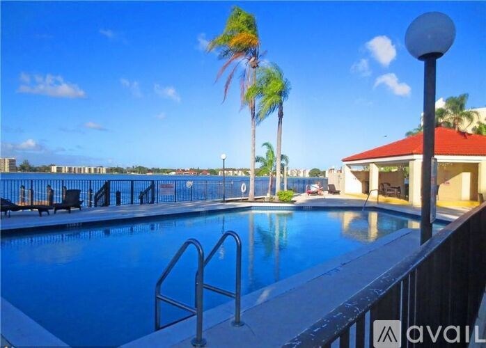 A pool surrounded by palm trees and a red roofed building.