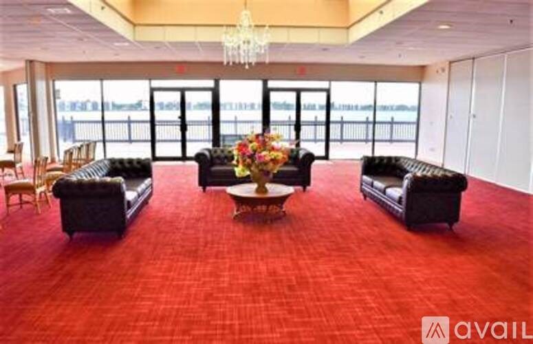A large room with a red carpet and black couches.