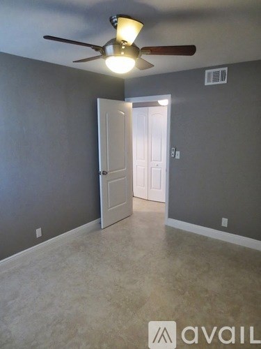 A room with a ceiling fan and a door leading to another room.