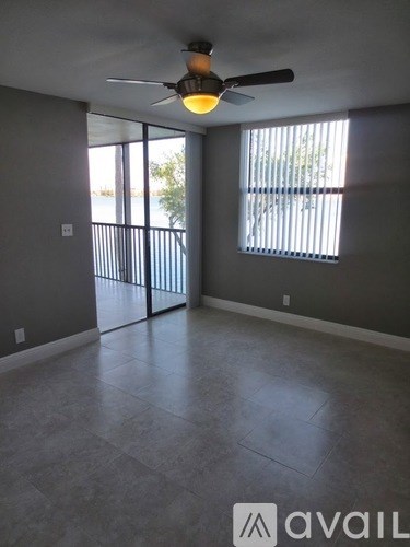 A room with a ceiling fan and sliding glass doors.