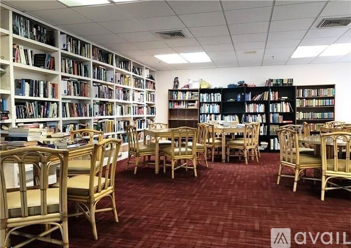 A library with rows of wooden chairs and bookshelves filled with books.