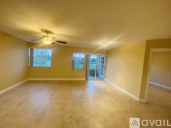 A spacious room with a ceiling fan and sliding glass doors leading to a balcony.