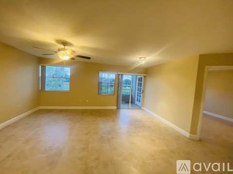 A spacious room with a ceiling fan and sliding glass doors leading to a balcony.