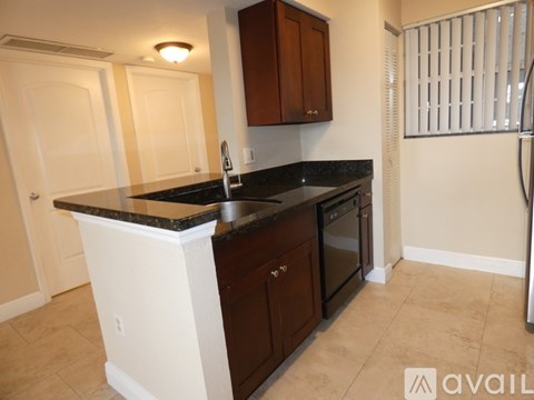 A kitchen with dark brown cabinets and a black countertop.