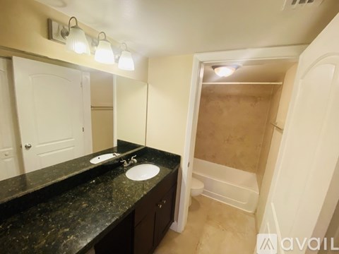 A bathroom with a sink, mirror, and shower.