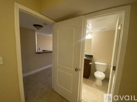 A bathroom with a toilet and sink is visible through an open door.