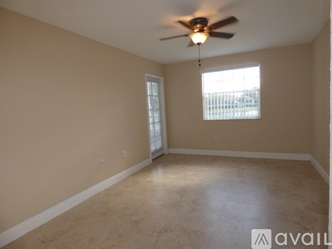 A room with a ceiling fan and two windows.