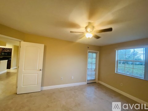 A spacious room with a ceiling fan and a door leading to another room.