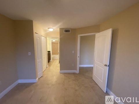 A room with beige walls and a tiled floor with a white door on the right.
