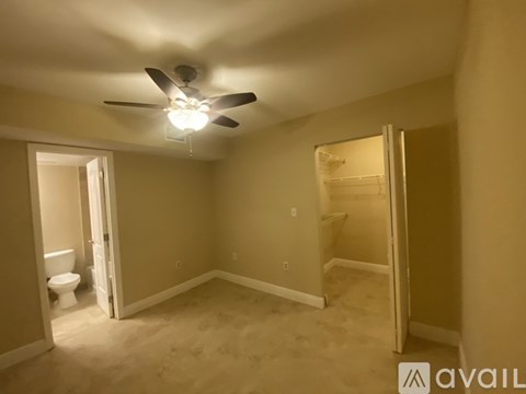 A room with a ceiling fan and a toilet in the corner.