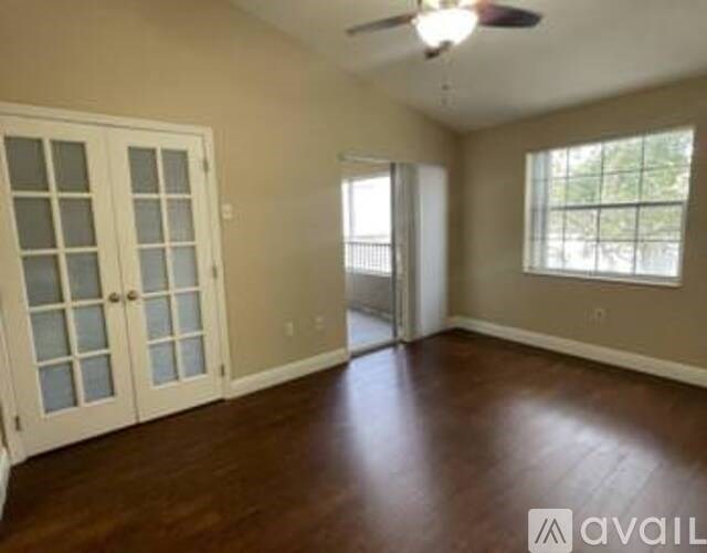A room with a ceiling fan and sliding glass doors.