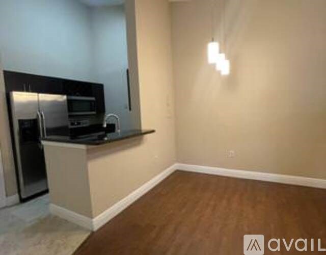 A kitchen area with a stainless steel refrigerator and a microwave on a countertop.