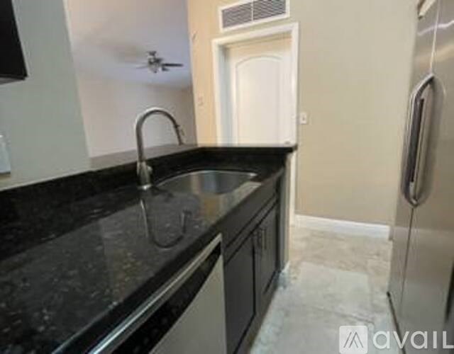 A kitchen with black granite countertops and a stainless steel refrigerator.
