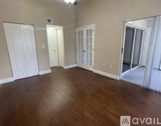 A room with wooden floors and three doors.