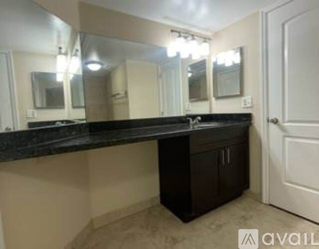 A bathroom vanity with a black countertop and a mirror above it.