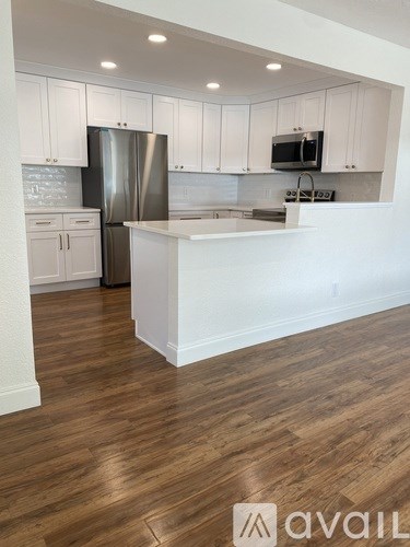 A kitchen with white cabinets and a wooden floor.
