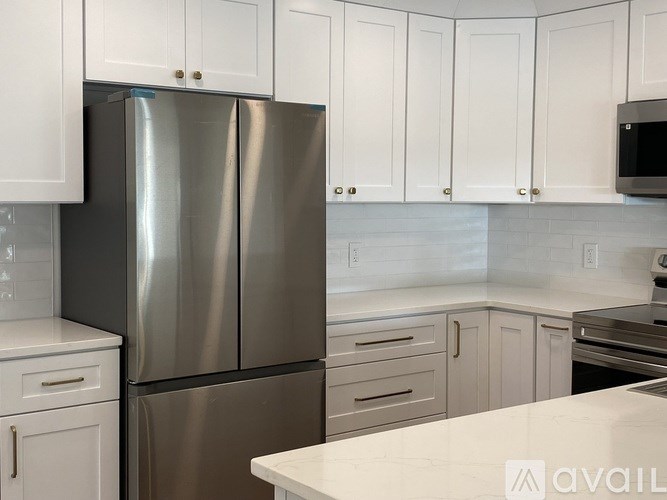 A kitchen with a stainless steel refrigerator and white cabinets.