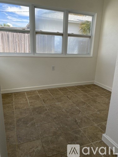 A room with a tiled floor and a window overlooking a wooden fence.