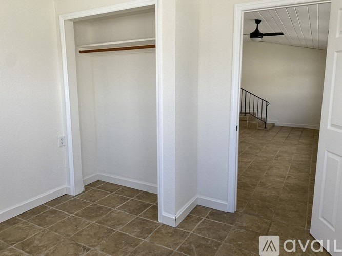 A room with a tiled floor and a closet with a shelf.