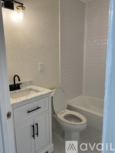 A white bathroom with a toilet, sink, and a shower.